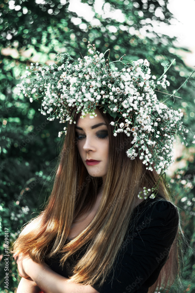 Amazing girl in a black dress and white wreath. Beautiful summer weather. Flowers. Amazing girl in a black dress and white wreath. Beautiful summer weather. Flowers.