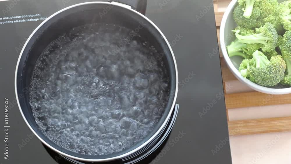 Boiling water at pan on Induction stove top panel for cooking broccoli, closeup Boiling water at pan on Induction stove top panel for cooking broccoli, closeup