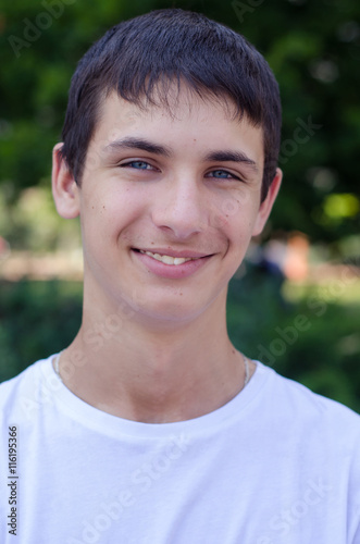 Close up portrait of a young smiling cute teenager with blue eye.