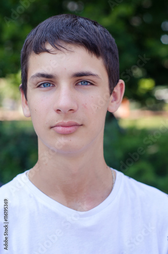 Close up portrait of a young smiling cute teenager with blue eye.