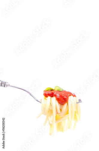 Forkful with succulent and tasty spaghetti with tomato sauce and basil