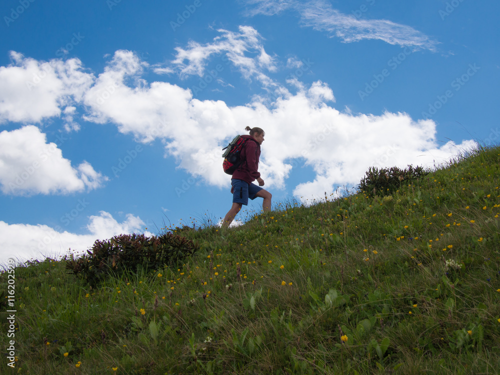 Woman going up the hill on a background of blue sky Woman going up the hill on a background of blue sky