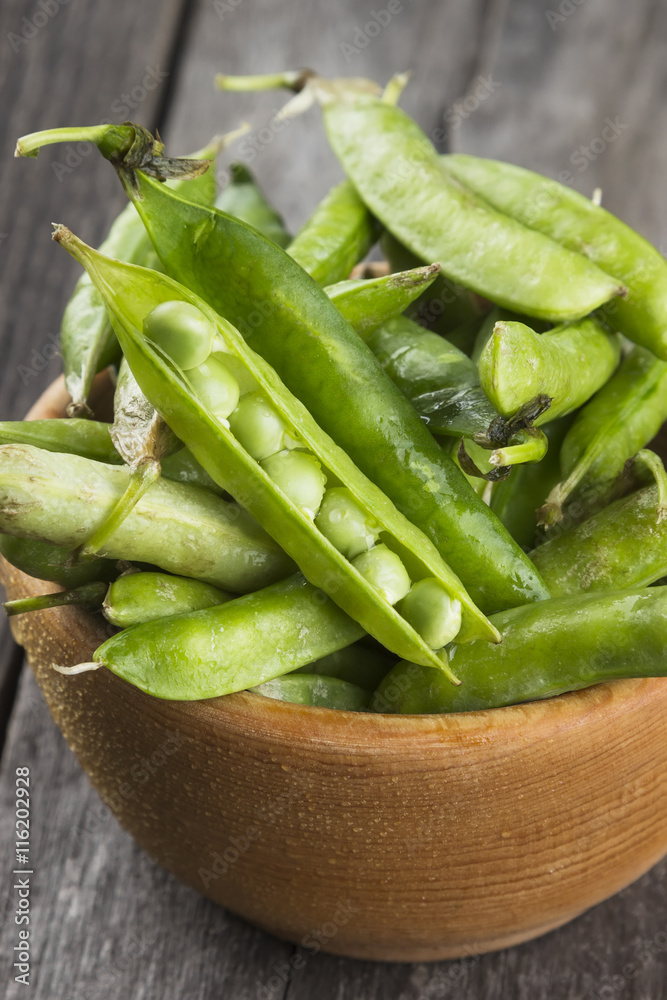 Green peas in wooden bowl on a white background Green peas in wooden bowl on a white background