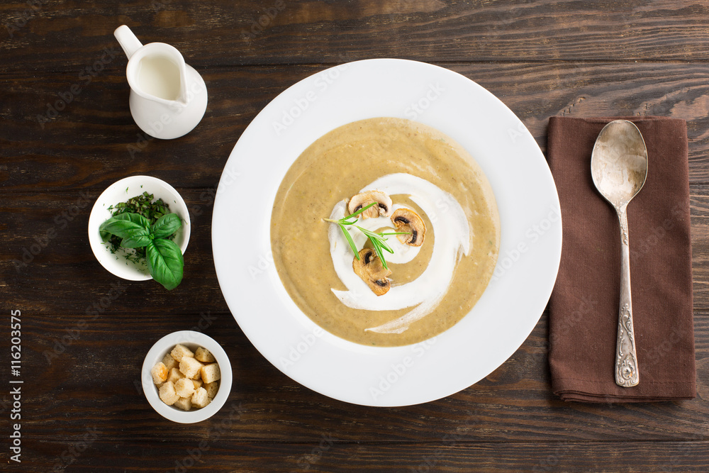 Mushroom cream soup with fried mushrooms and fresh herbs on rustic white wooden table, top view Mushroom cream soup with fried mushrooms and fresh herbs on rustic white wooden table, top view