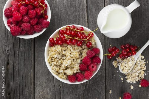 Oatmeal with raspberry and red currant on a wooden background