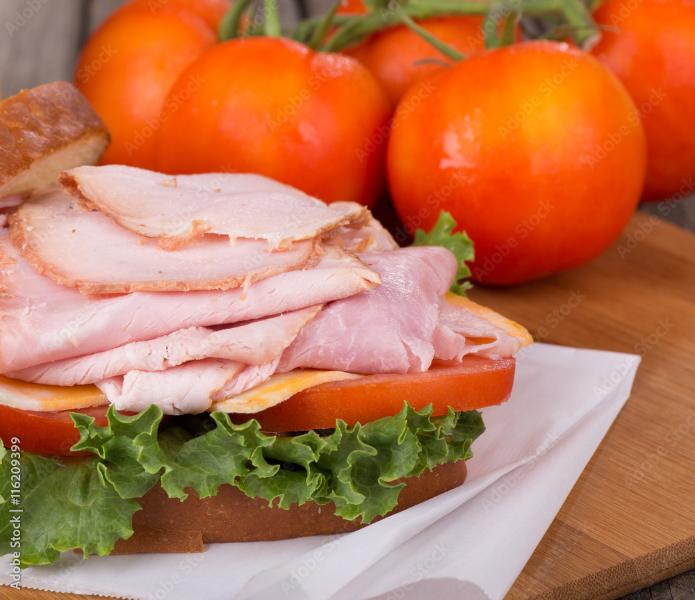 Ham Sandwich Closeup With Ripe Vine Tomatoes in Background