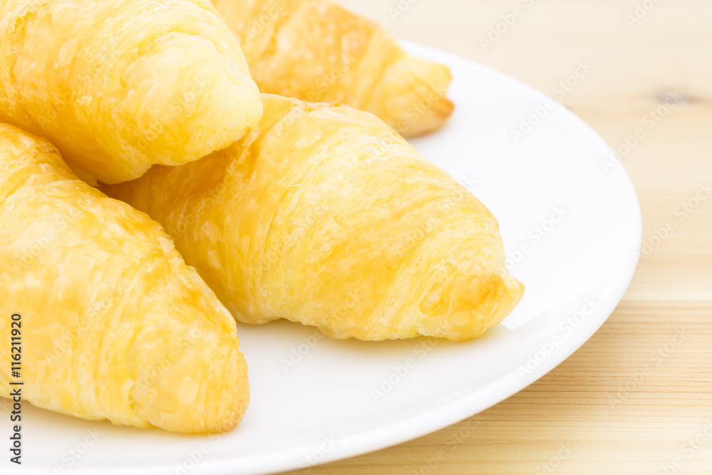 Croissant or Bread on White Dish on Wood Table Croissant or Bread on White Dish on Wood Table
