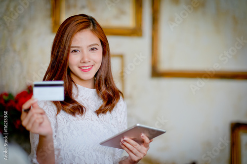 Happy woman shopping online, holding credit card, using tablet c