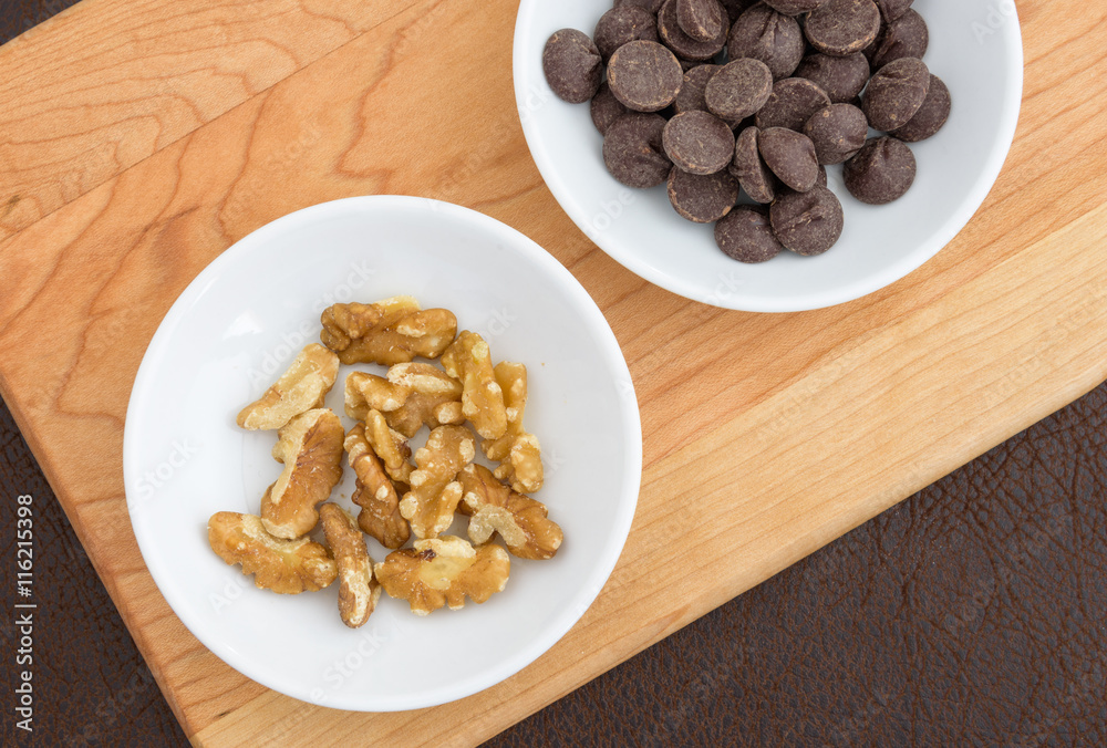 Walnuts, and chocolate chips laid out on a cutting board to make a tasty treat
Walnuts, and chocolate chips laid out on a cutting board to make a tasty treat