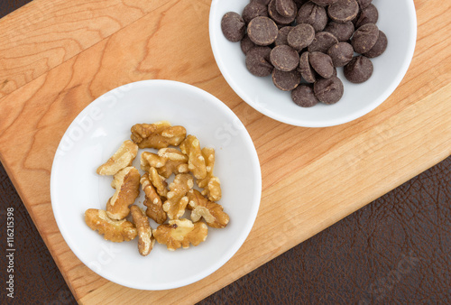 Walnuts, and chocolate chips laid out on a cutting board to make a tasty treat
