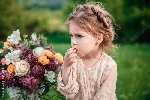 Little baby girl eats chocolate cake in nature at a picnic. The concept of a happy childhood