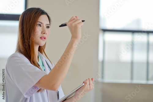 Portrait of cheerful female doctor with clipboard showing blank area for sign or copyspace