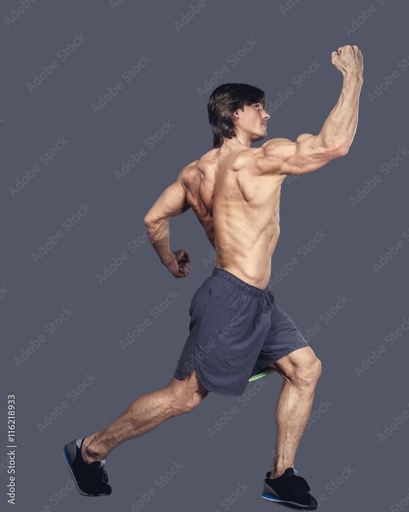 Shirtless muscular male in action isolated on a grey background.
