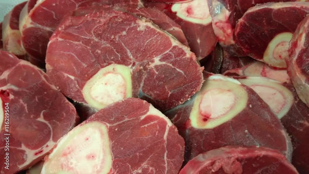 Lots of raw osso buco meat, inside a metal container