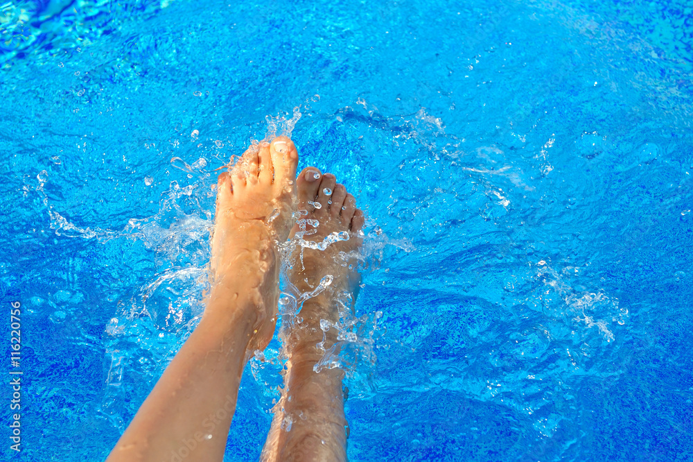 Sexy women legs splashing in tropical swimming pool