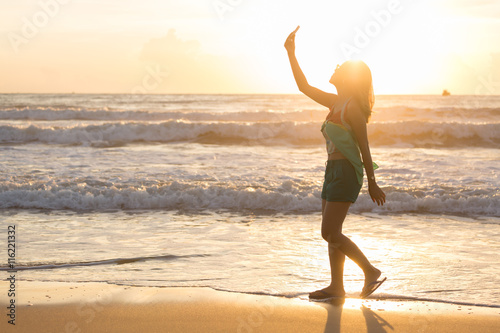 woman travel enjoy take a photo selfie on the beach with sunrise