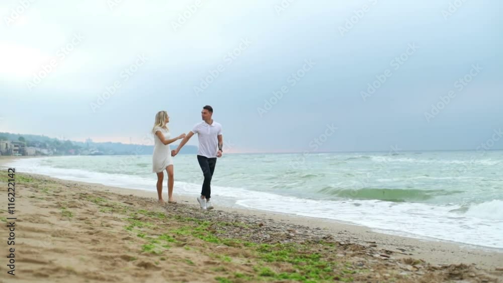 young couple runs along the sea then man spins and kisses woman slow motion young couple runs along the sea then man spins and kisses woman slow motion