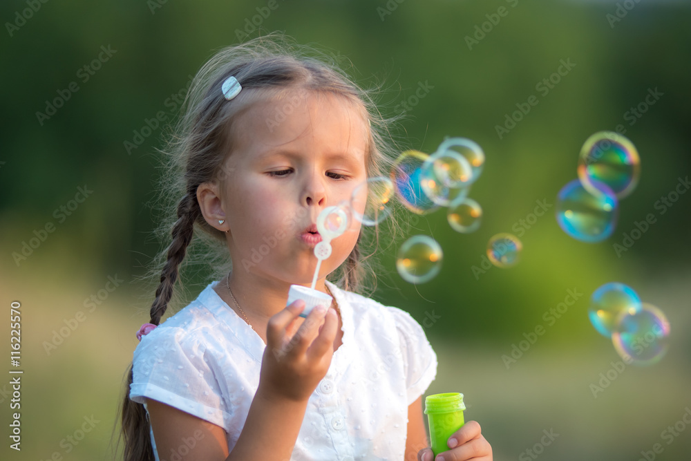The cute girl blow bubbles on the nature