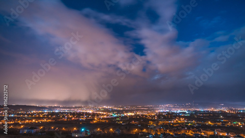 The beautiful night view on the city against the background of cloud stream. Wide angle