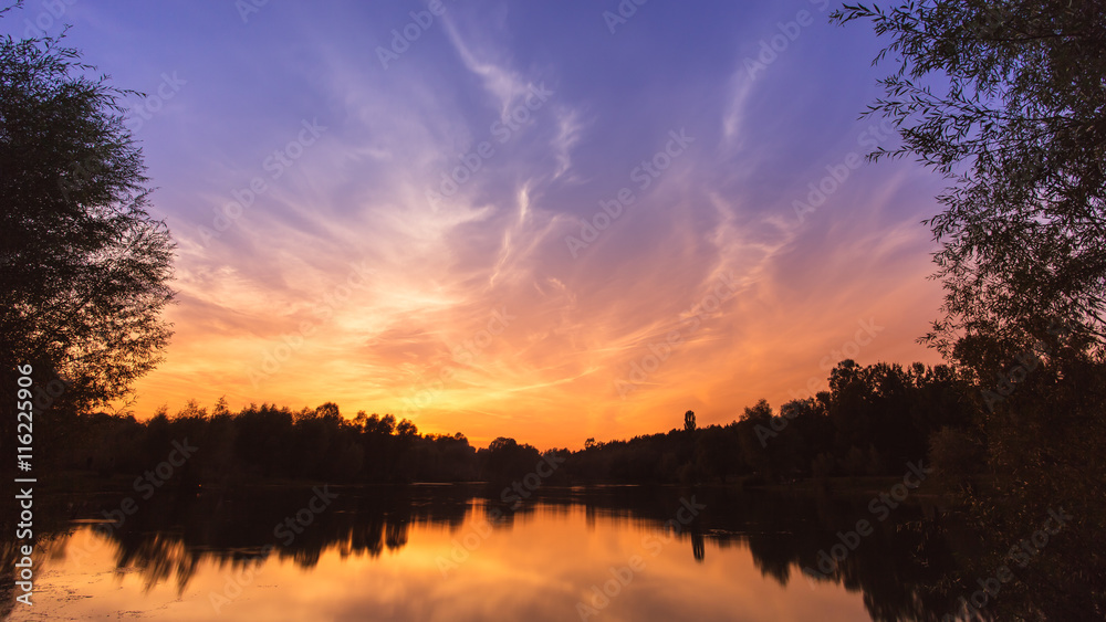 Picturesque sunset (sunrise) above land, river and forest. Wide angle