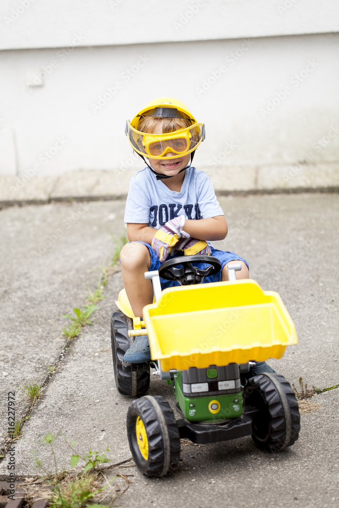 Kleiner Junge auf seinem Spielzeug Traktor Kleiner Junge auf seinem Spielzeug Traktor