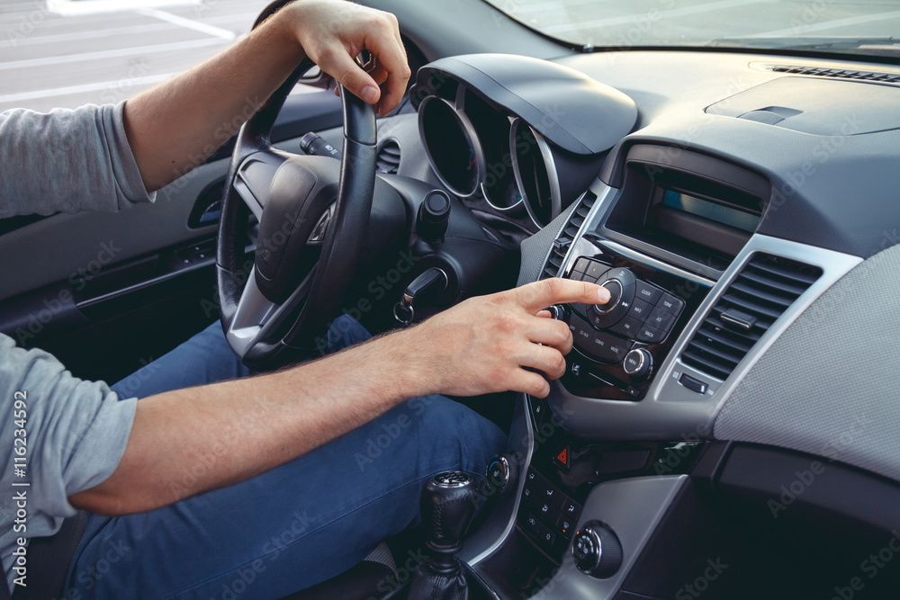 Naklejka premium Car dashboard. Radio closeup. Man sets radio