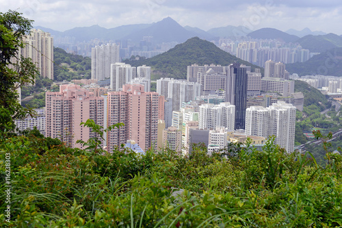 Crowded Hong Kong scene with tightly packed skyscrapers and apartment buildings with green tropical mountain background