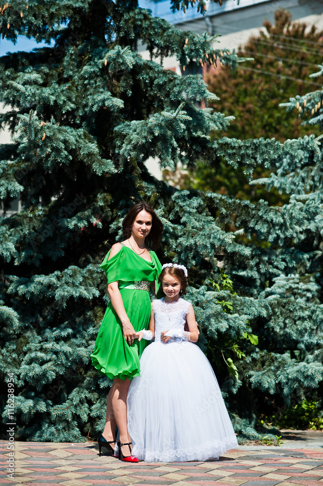 Fototapeta premium Mother and daughter at white and green dress at sunny day
