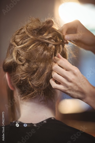 Female hairdresser styling customers hair