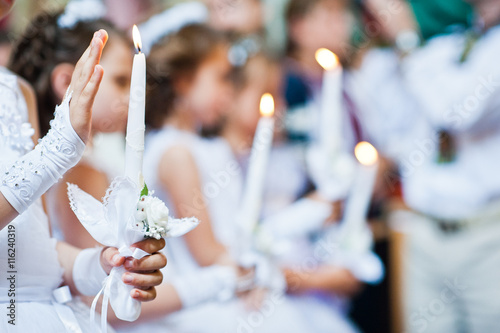 Hands with candles of little girls on first holy communion