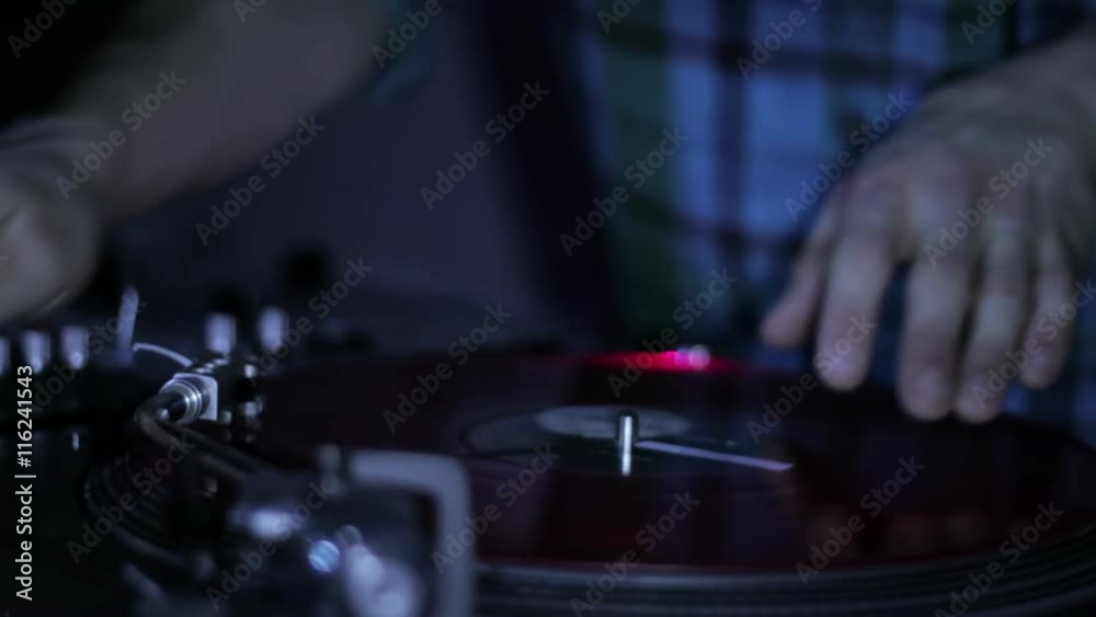 DJ scratching vinyl records and mixing on the Decks at a disco in Nightclub DJ scratching vinyl records and mixing on the Decks at a disco in Nightclub