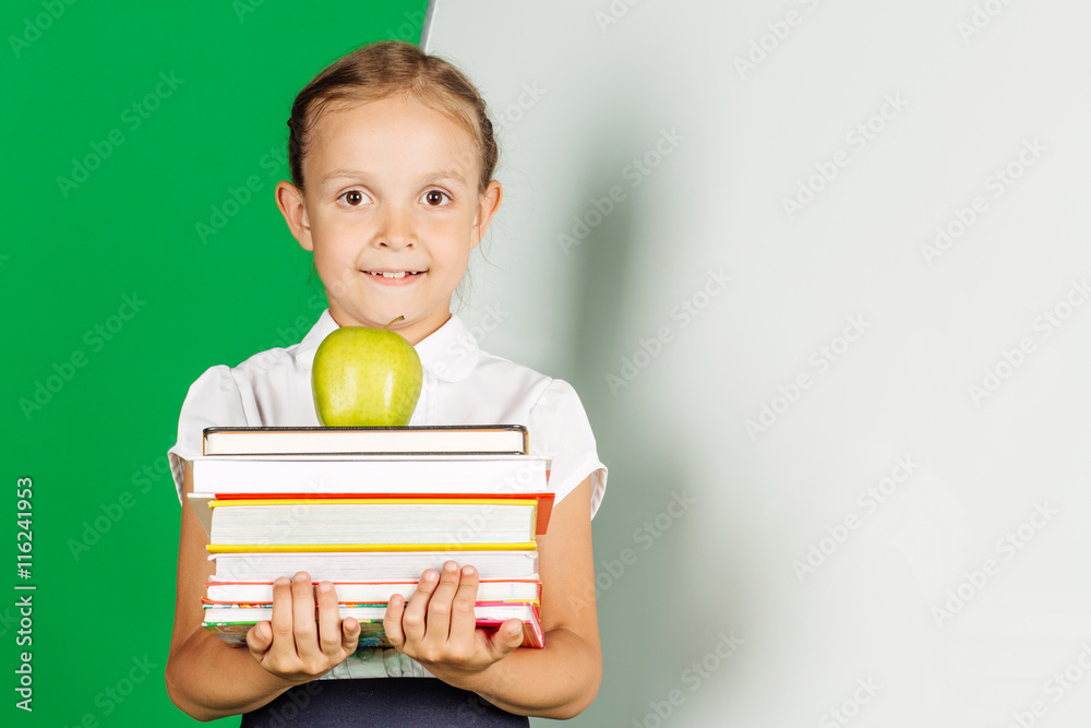 girl in a school uniform holding a stack of books and green apple girl in a school uniform holding a stack of books and green apple