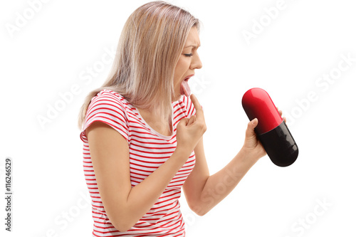 Sick young woman holding a pill