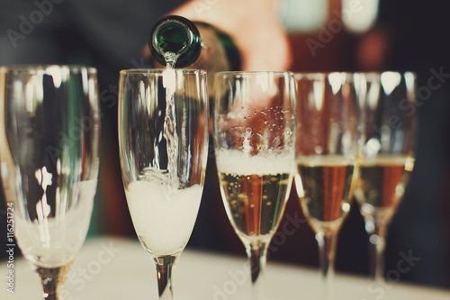 Man pours champagne in wineglasses photo