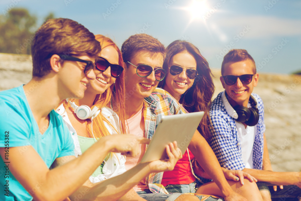 group of smiling friends with tablet pc outdoors