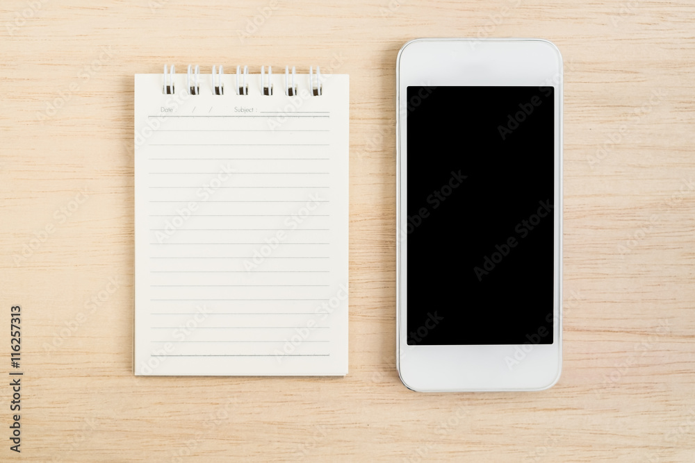 Top view of office desk with mobile phone and spiral notebook on Top view of office desk with mobile phone and spiral notebook on