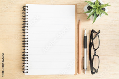 Top view of open spiral notebook with brown pencil, pen, black e