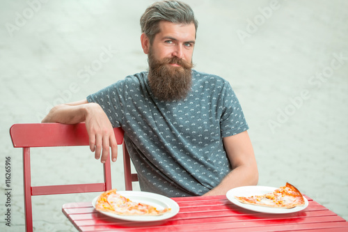 handsome bearded man with pizza in cafe