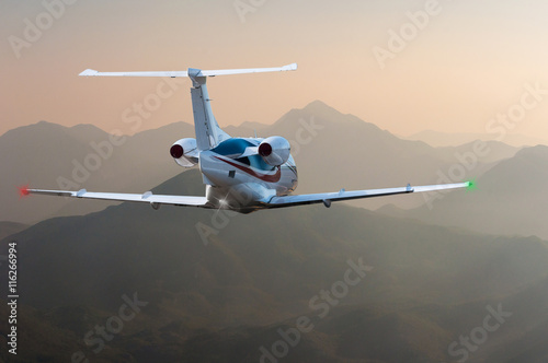 Airplane flying above Alps or other mountain at sunset. Travel concept