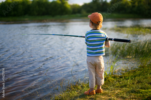 first fishing. child standing with a fishing rod on the shore
