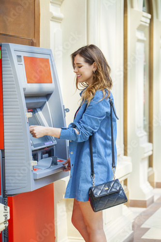 Cuadro en lienzo Happy brunette woman withdrawing money from credit card at ATM