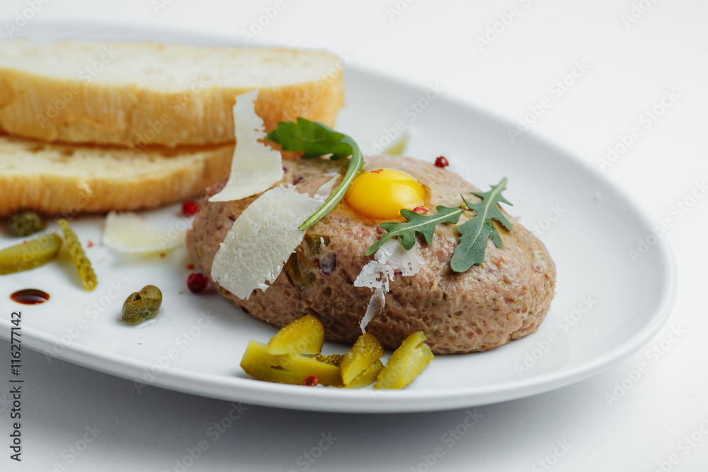 Meat cutlet with pickled cucumbers, fresh herbs and bread on a white plate closeup