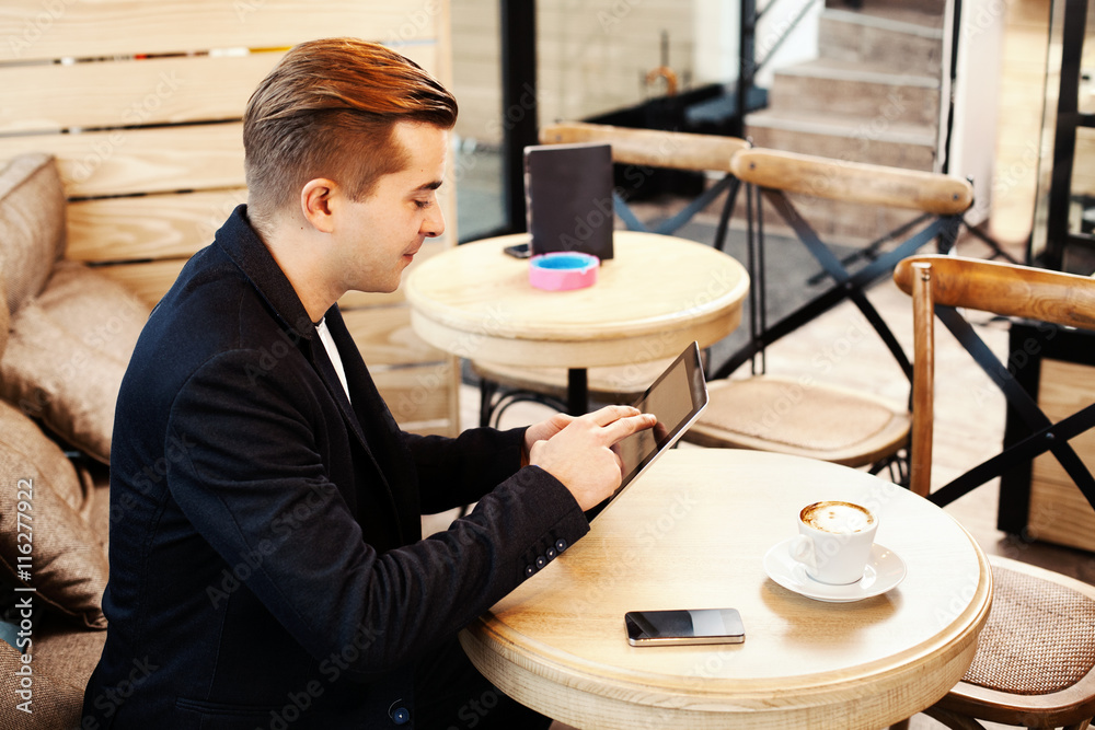Young man using digital tablet in caffe Young man using digital tablet in caffe