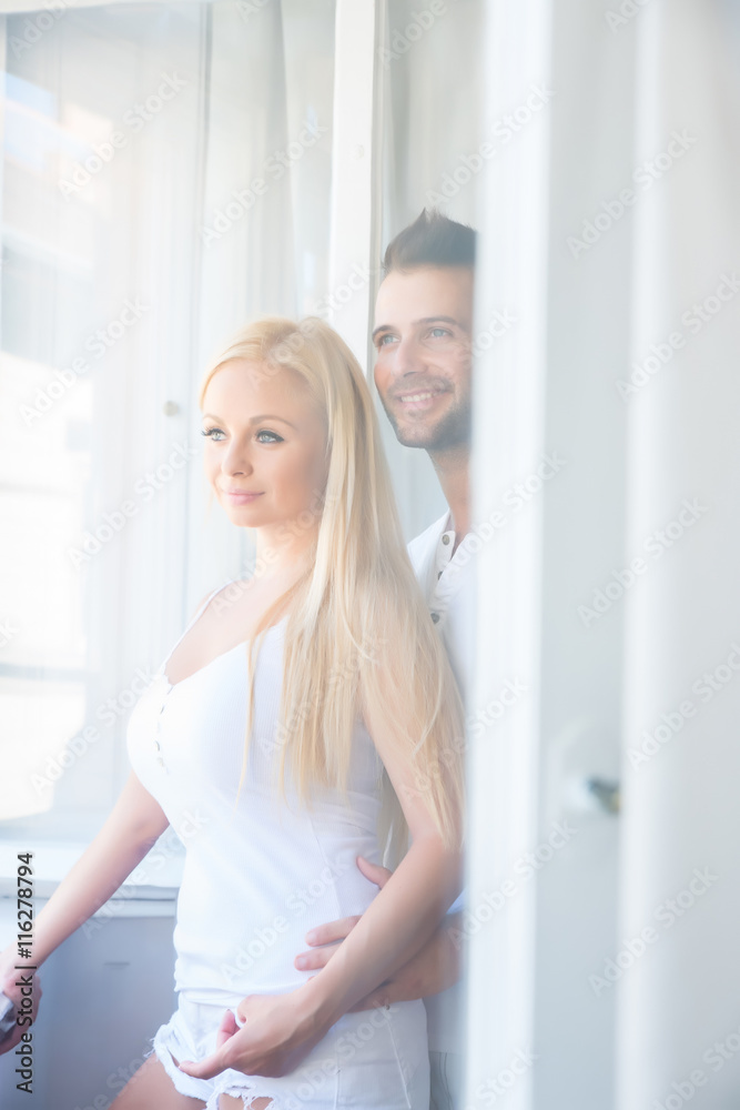Beautiful young couple standing at the window		