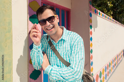 Young stylish confident happy laughing handsome man model in blue t-short with sunglasses. pattern background photo