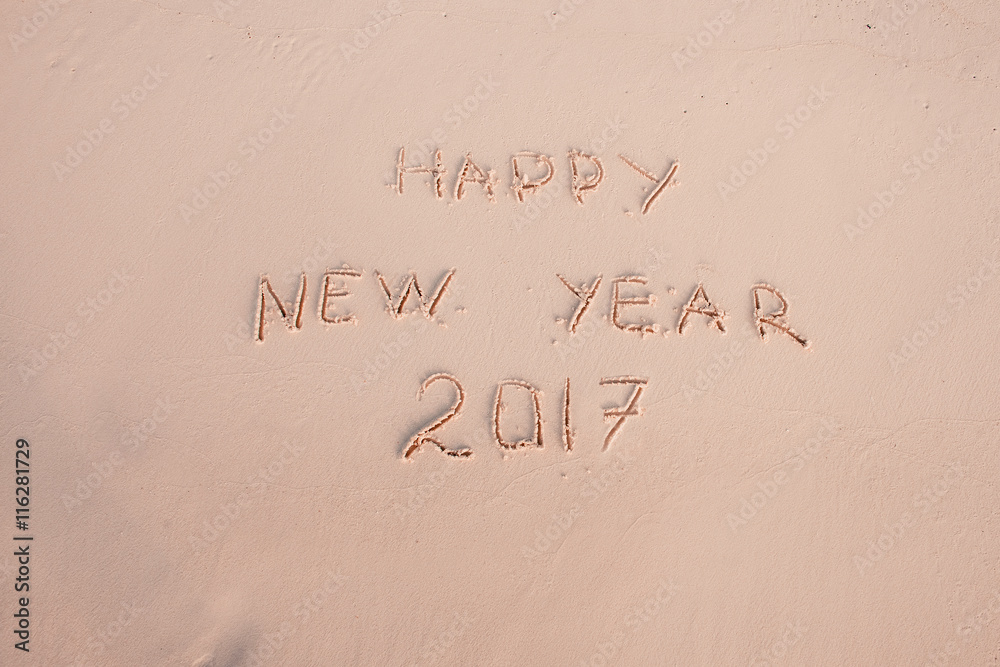 2016 2017 inscription written in the wet yellow beach sand being washed with sea water wave. Concept of celebrating the New Year at some exotic place