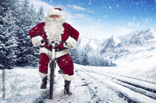 Santa Claus on a bike on a snow covered road on a snowy cold winter christmas day. 