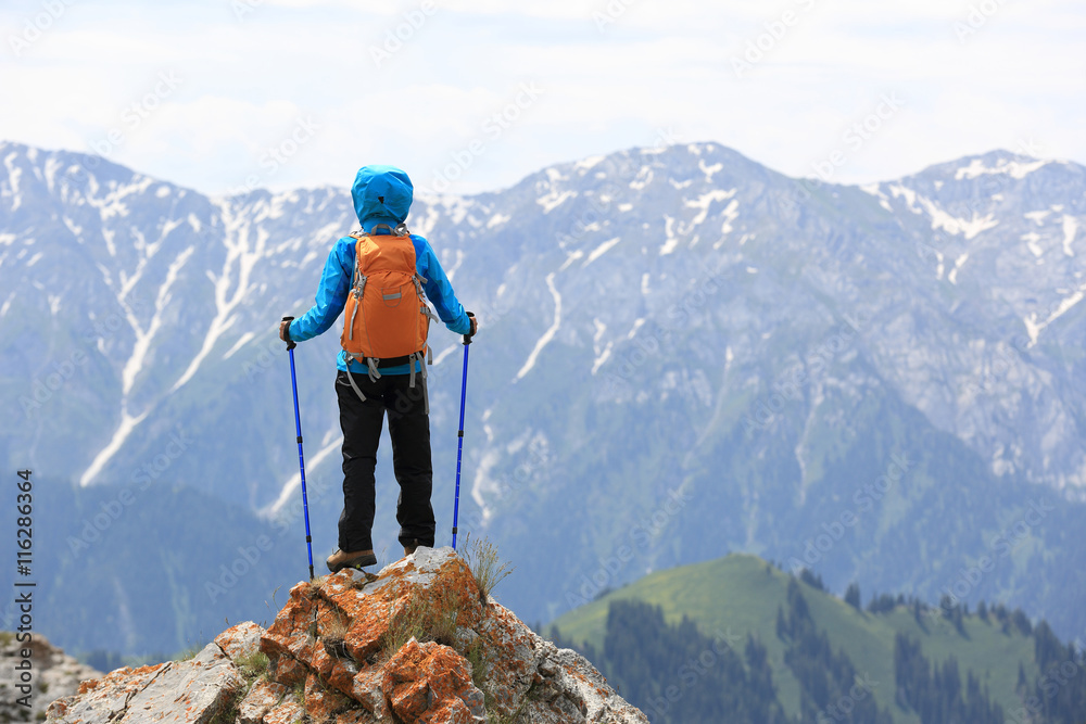 successful woman backpacker enjoy the view on mountain peak cliff