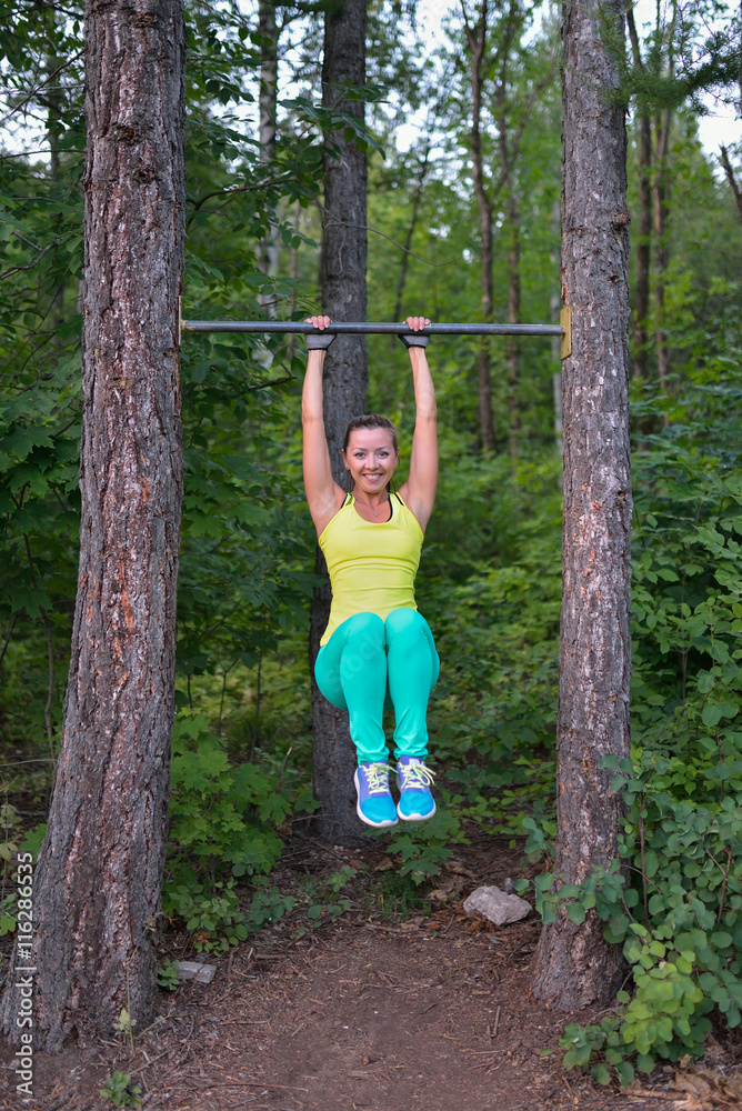 Fit woman preparing to do pull ups on horizontal bar