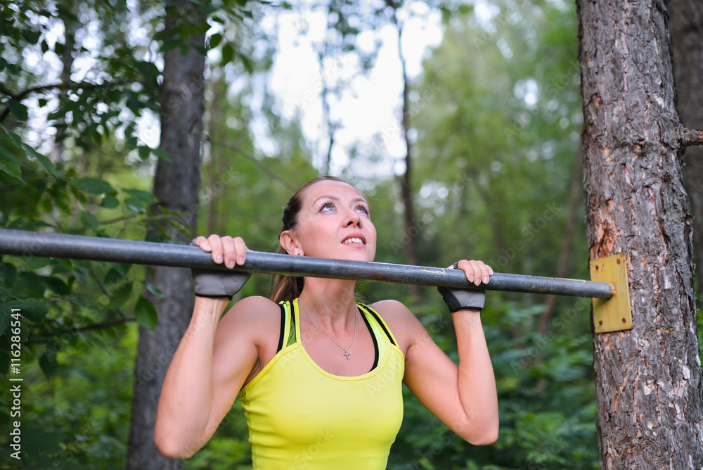 Fit woman training pull ups on horizontal bar in city park outdoors Fit woman training pull ups on horizontal bar in city park outdoors